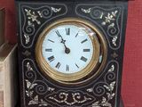 une horloge noire et dorée posée à côté d'une pile de livres
