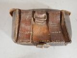 a small brown purse with a handle on a white surface