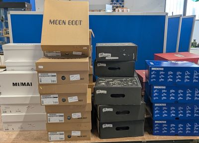 Plusieurs cartons de vêtements pour hommes sont empilés sur une étagère dans un magasin.
