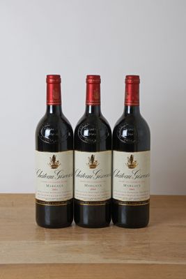 trois bouteilles de vin rouge sont posées sur une table en bois