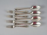 six cuillères en argent et une fourchette sont alignées sur une table