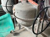 a cement mixer sitting in a garage next to other items