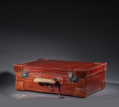 une valise marron munie d'une poignée, posée sur une surface grise