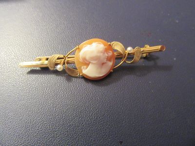 une image représentant une barrette de couleur dorée ornée d'un camée représentant une femme