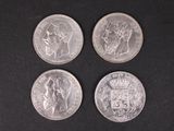 four silver coins are shown on a black surface