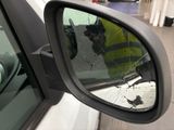 a man in a yellow vest taking a picture of himself in the side view mirror of a car