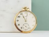 a gold pocket watch sitting on a marble block