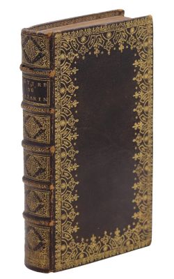 un vieux livre avec des bordures dorées et une couverture noire sur fond blanc
