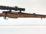 le fusil est posé sur un support transparent équipé d'une lunette de visée