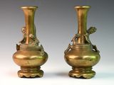 two bronze vases sitting side by side on a white surface
