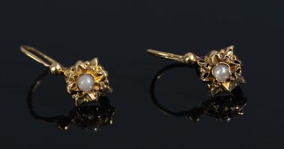 a pair of gold and pearl earrings on a black surface