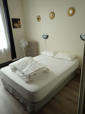un lit recouvert de draps blancs dans une petite chambre