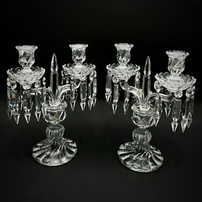 deux chandeliers en verre transparent avec des bougies, sur fond noir