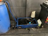 un conteneur bleu muni d'un tuyau, à côté d'un fût bleu
