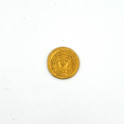 l'image d'une pièce d'or posée sur une surface blanche