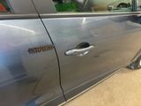 a silver car with a door handle and a sticker on it