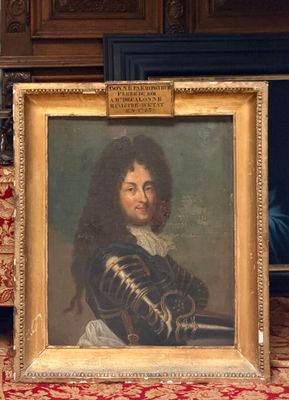 portrait d'un homme en manteau noir, dans un cadre doré, posé sur un tapis rouge