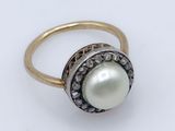 a close up of a pearl and diamond ring on a white surface