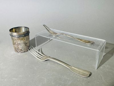 une fourchette et une cuillère posées sur une table, à côté d'une tasse