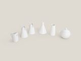 Plusieurs vases blancs sont disposés en rangée sur une surface grise