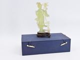 statue d'une femme posée sur une boîte bleue contenant une plante