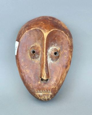 une image représentant un masque en bois sur fond gris