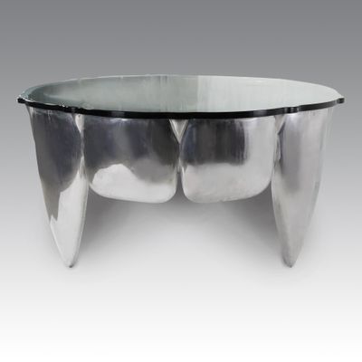 une table basse ovale en verre, avec un piètement en métal et un plateau en verre transparent