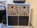 une armoire blanche surmontée de paniers en osier