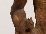 a statue of a squirrel holding a bird on its back