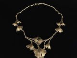 a gold necklace with leaves and flowers on a black background