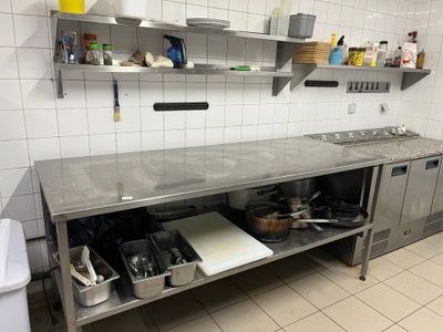 une cuisine équipée de plans de travail et d'étagères en acier inoxydable