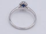 a close up of a diamond and sapphire ring on a white surface