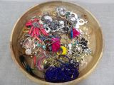 a wooden bowl filled with assorted jewelry on a table