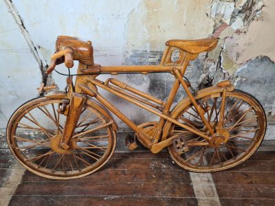 a wooden bicycle that is leaning against a wall