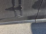 a reflection of a person holding a surfboard on the side of a car