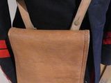 a brown bag on a mannequin stand next to a pair of shoes
