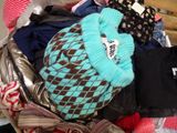 un tas de vêtements dans un panier, avec un chapeau posé dessus