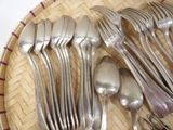 a lot of silver spoons and forks in a basket
