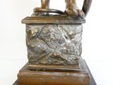 une statue en bronze représentant un chat assis sur une boîte