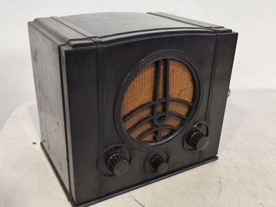 une vieille radio noire posée sur une table blanche