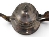 a silver teapot with a wooden handle on a white surface