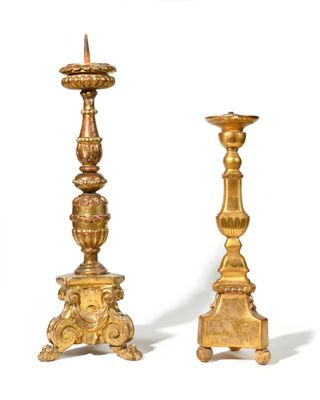 pair of antique brass candlesticks on pedestals against a white background