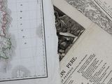de nombreuses cartes anciennes posées sur une table recouverte de papiers