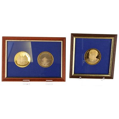 Deux pièces d'or et d'argent, encadrées, sont exposées dans une vitrine.