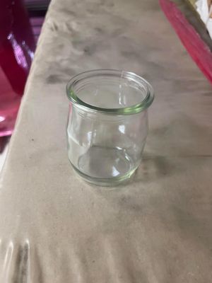 un petit bocal en verre posé sur une table à côté d'une assiette de nourriture