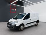 La camionnette blanche est garée dans une grande pièce où se trouve un panneau rouge.