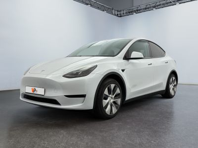 the white tesla model y is parked in a white room