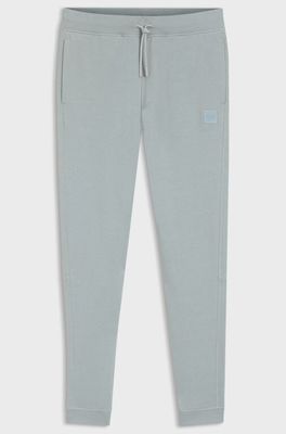 une photo d'un pantalon de survêtement gris pour petit garçon, avec un petit patch sur le côté