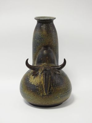 un vase marron orné de cornes, posé sur un fond blanc