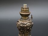 une lampe à huile en laiton ancien posée sur une surface noire